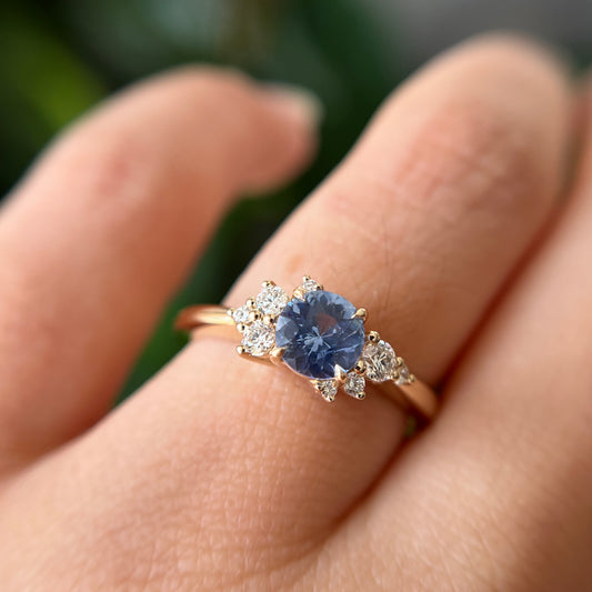 Bague de fiançailles en saphir bleu cornflower et diamants en or jaune 14k, portée au doigt montrant la couleur de la pierre et le détail des diamants