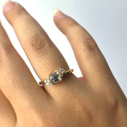 Bague unique en or jaune avec saphir vert et grappe de diamants, portée sur le doigt