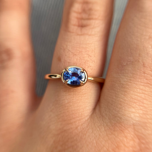 0.61ct unheated oval royal blue sapphire solitaire ring in 14k yellow gold, worn on hand showing stone colour and gold frame setting