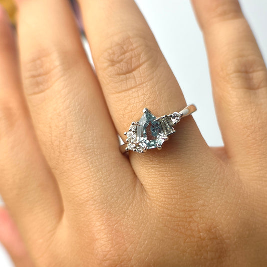 1.27ct step-cut pear shape teal Madagascar sapphire and diamond ring in platinum, worn on hand showing stone colour and eagle claw setting