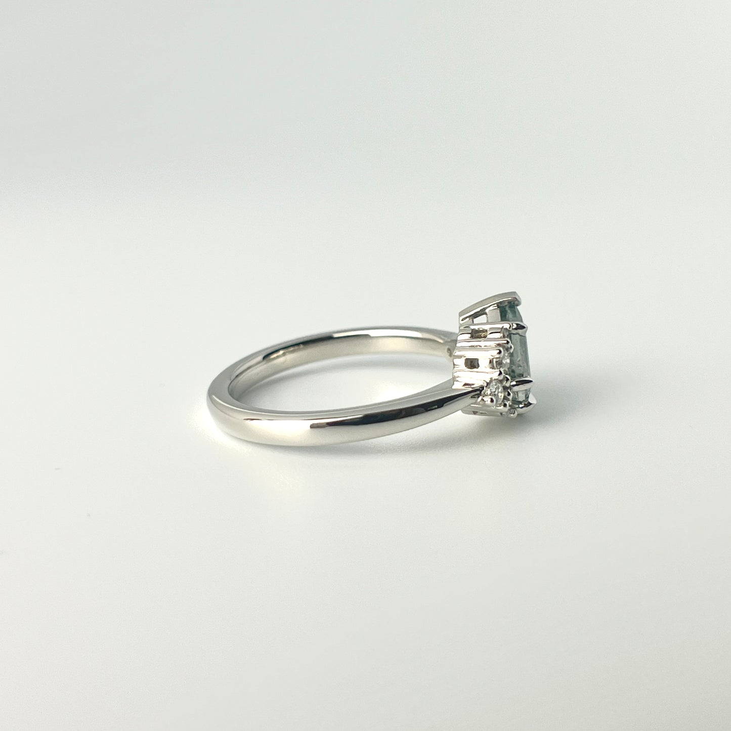 1.27ct step-cut pear shape teal Madagascar sapphire and diamond ring in platinum, side view showing band profile and setting detail