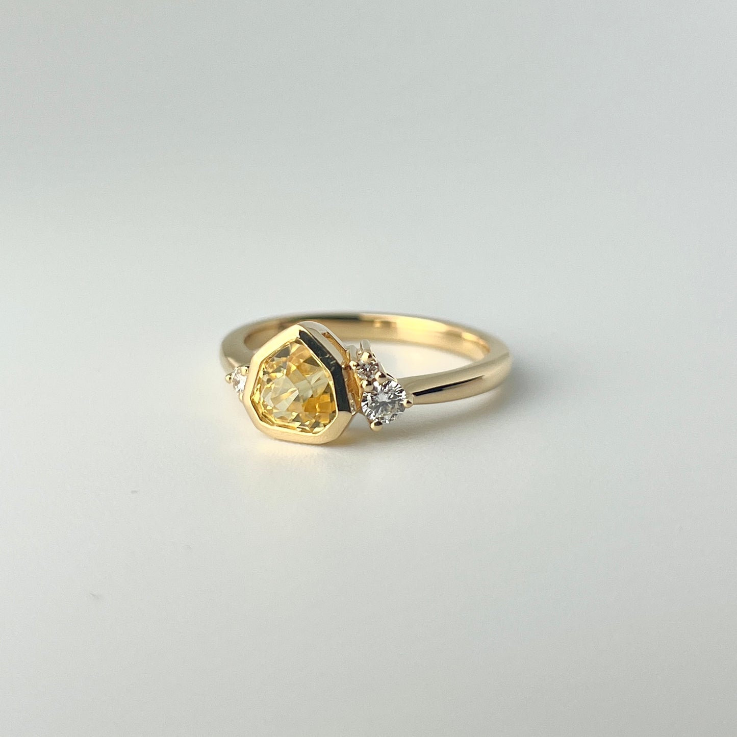 1.18ct mixed-cut trillion shaped bright yellow Sri Lankan sapphire and diamond ring in 18k yellow gold, front angled view showing bezel setting and diamond accents