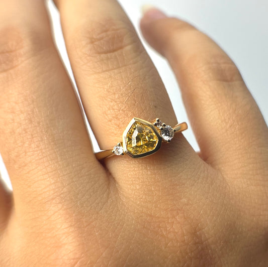 1.18ct mixed-cut trillion shaped bright yellow Sri Lankan sapphire and diamond ring in 18k yellow gold, worn on hand showing stone colour and bezel setting