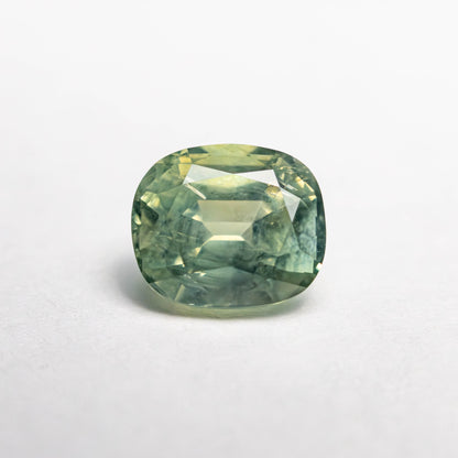 1.47ct unheated cushion cut green Montana sapphire, loose stone on white background showing colour and faceting