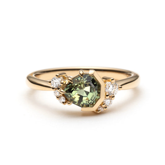 Gold ring with a green sapphire and diamond accents on a white background
