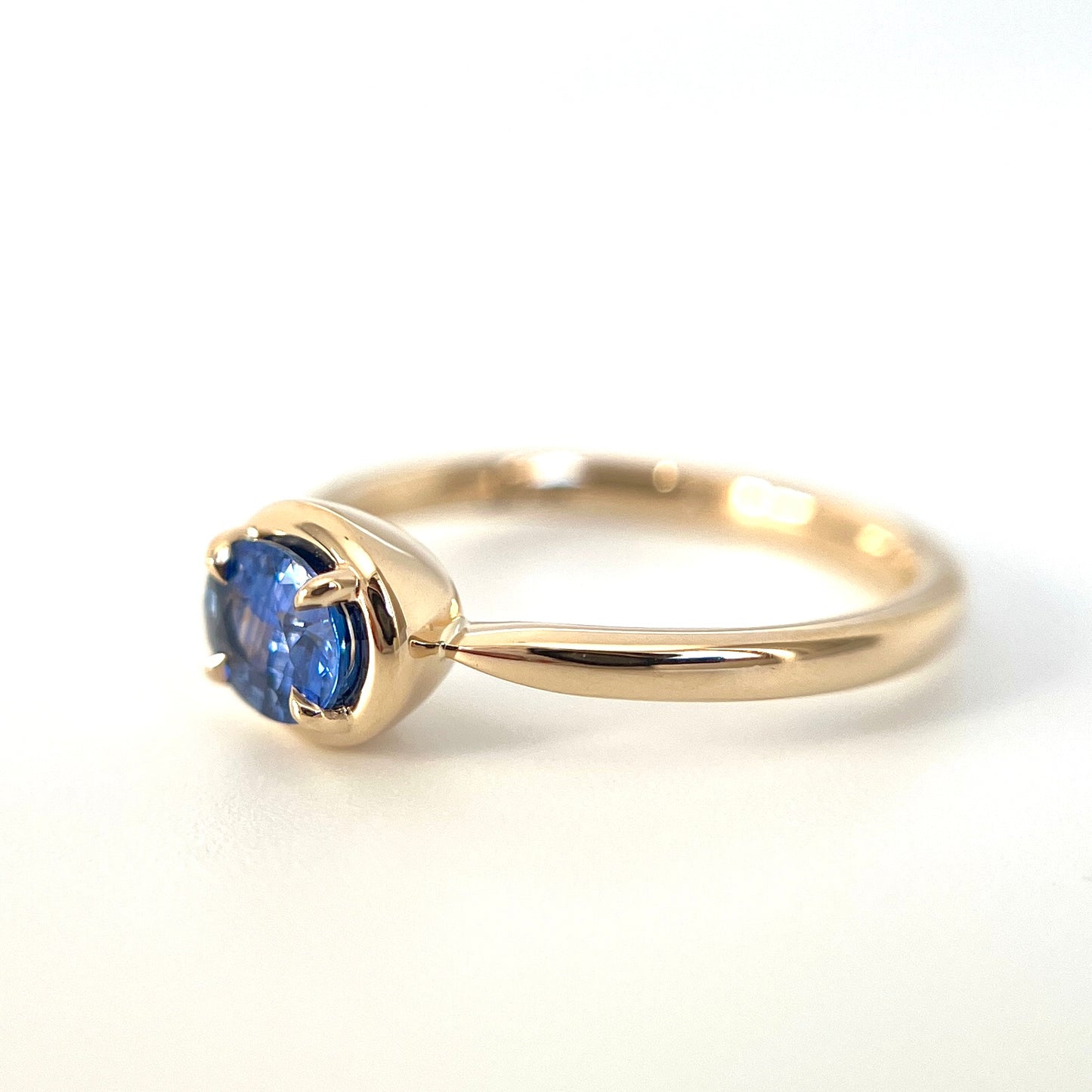 0.61ct unheated oval royal blue sapphire solitaire ring in 14k yellow gold, side view showing gold frame setting and band profile