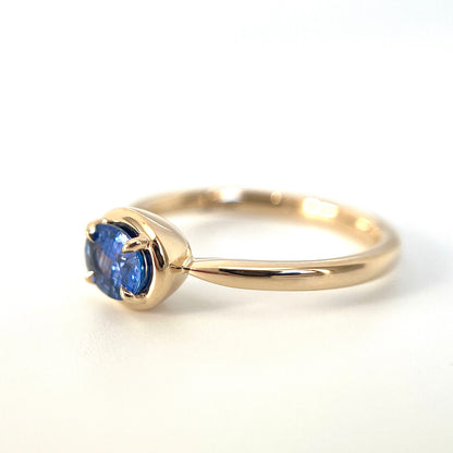 0.61ct unheated oval royal blue sapphire solitaire ring in 14k yellow gold, side view showing gold frame setting and band profile
