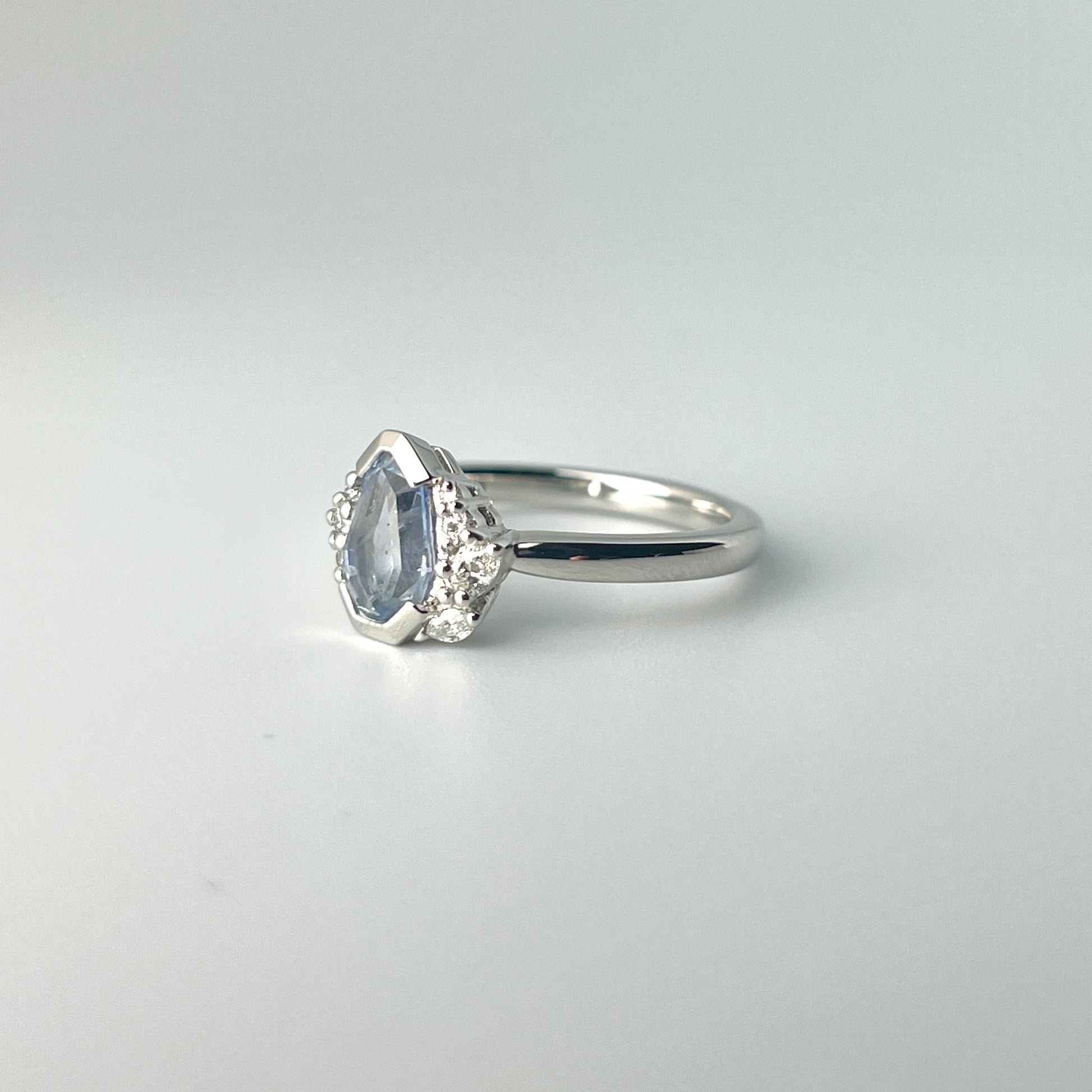 One-of-a-kind light blue sapphire engagement ring in platinum with asymmetrical diamond cluster