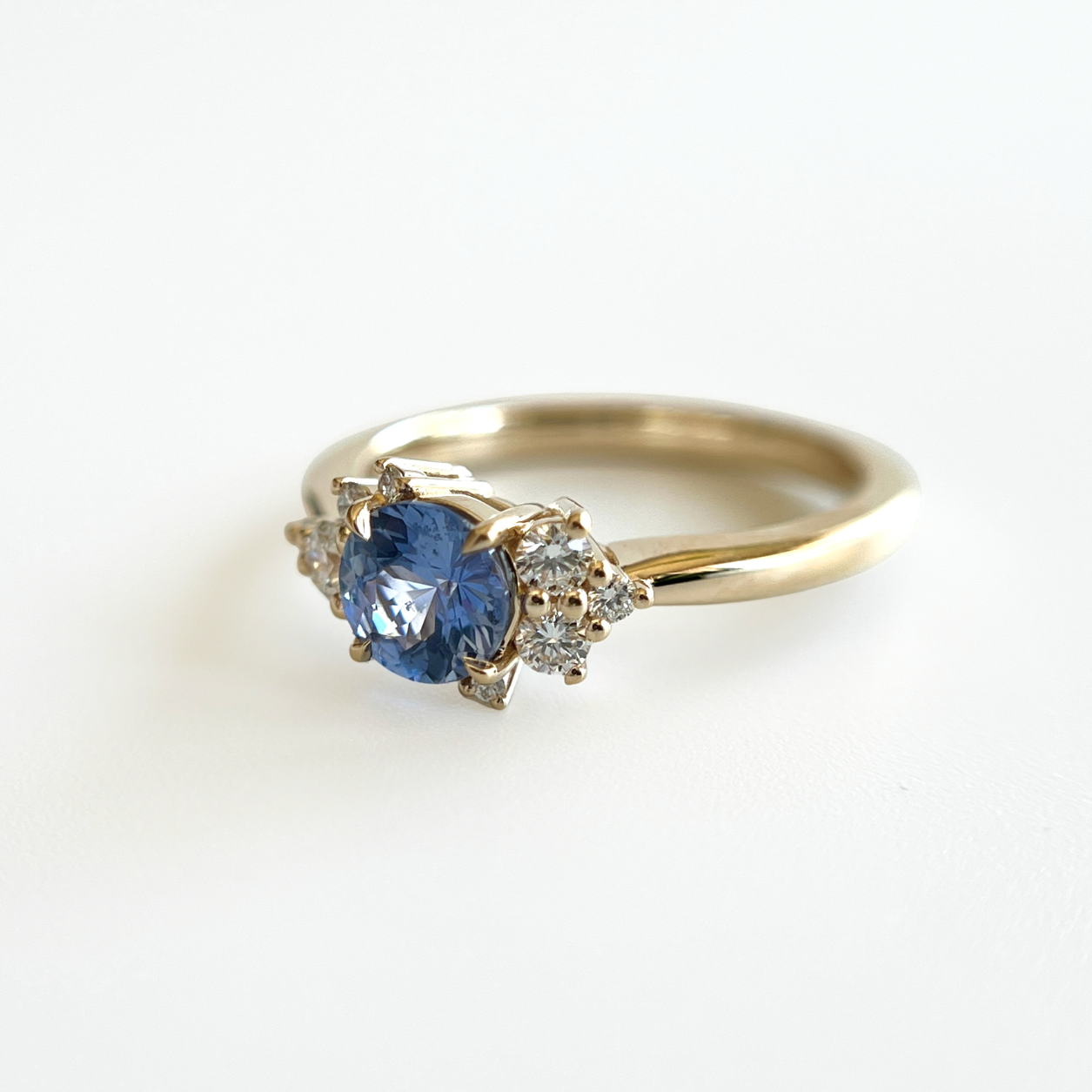 Bague de fiançailles en saphir bleu cornflower et diamants en or jaune 14k, vue de côté montrant le serti asymétrique