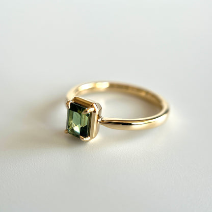 Bague de fiançailles solitaire en saphir vert forêt taille émeraude de 1,05ct de Madagascar en or jaune 14k, vue en angle montrant le détail du serti en griffes à cadre en or