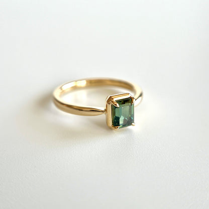 Bague de fiançailles solitaire en saphir vert forêt taille émeraude de 1,05ct de Madagascar en or jaune 14k avec serti en griffes à cadre en or, vue en angle sur fond blanc