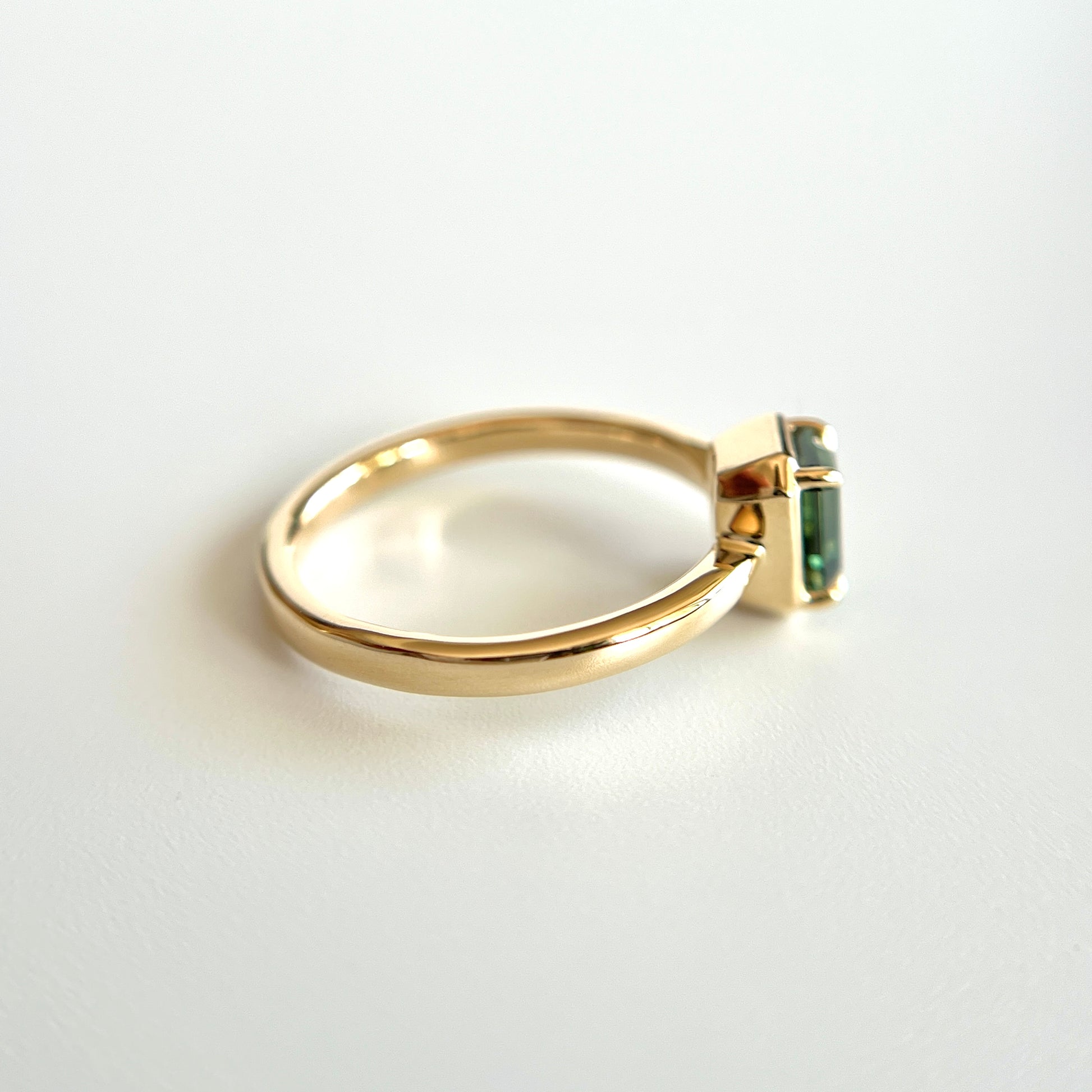Bague de fiançailles solitaire en saphir vert forêt taille émeraude de 1,05ct de Madagascar en or jaune 14k, vue de côté montrant le profil du corps de bague et la hauteur du serti