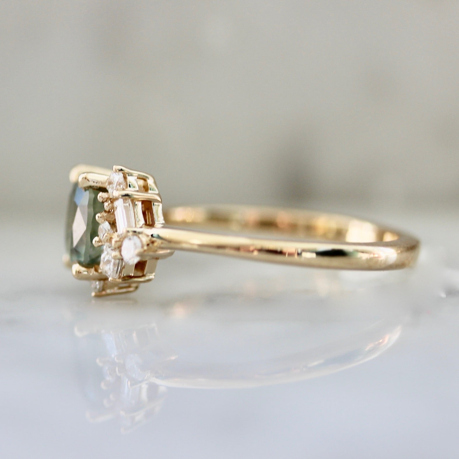1.47ct unheated cushion cut green Montana sapphire and diamond cluster ring in 14k yellow gold, side view showing asymmetric diamond setting and band profile