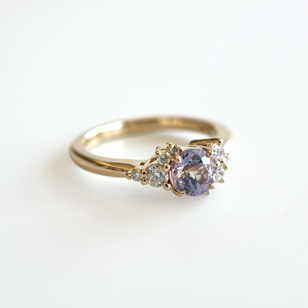 Bague de fiançailles en saphir violet clair et diamants en or jaune 14k, vue en angle montrant le serti asymétrique
