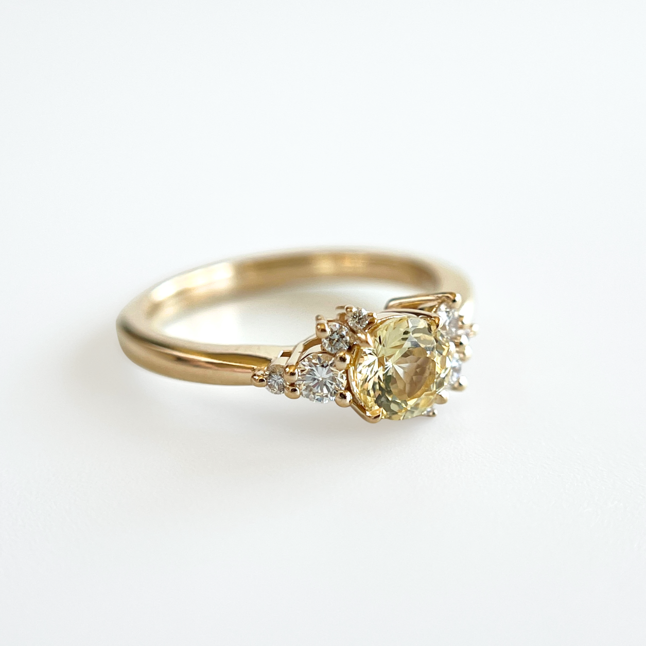 Bague de fiançailles en saphir jaune clair et diamants en or jaune 14k, vue en angle montrant le serti asymétrique