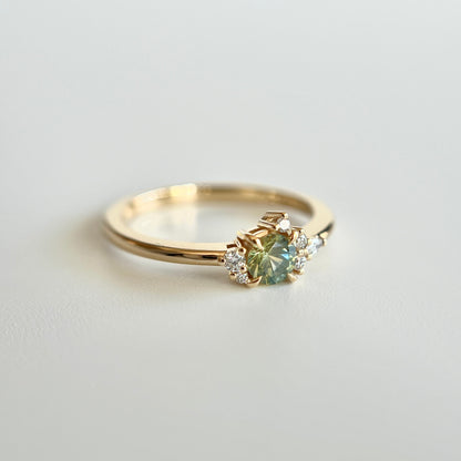 Bague de fiançailles en saphir bicolore rond de 0,36ct passant du jaune au bleu et diamants naturels en or jaune 14k, vue en angle montrant le changement de couleur de la pierre et le détail du cluster asymétrique