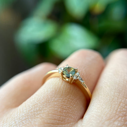 Bague de fiançailles en saphir bicolore rond de 0,36ct passant du jaune au bleu et diamants naturels en or jaune 14k, vue de côté portée au doigt montrant le profil du corps de bague et le changement de couleur de la pierre