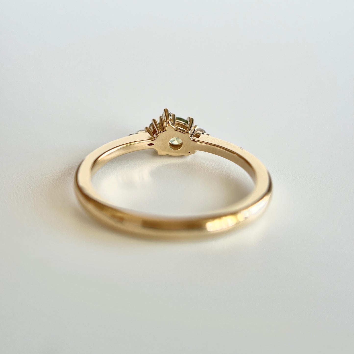 Bague de fiançailles en saphir bicolore rond de 0,36ct passant du jaune au bleu et diamants naturels en or jaune 14k, vue du dessous montrant la construction du serti et le détail du corps de bague