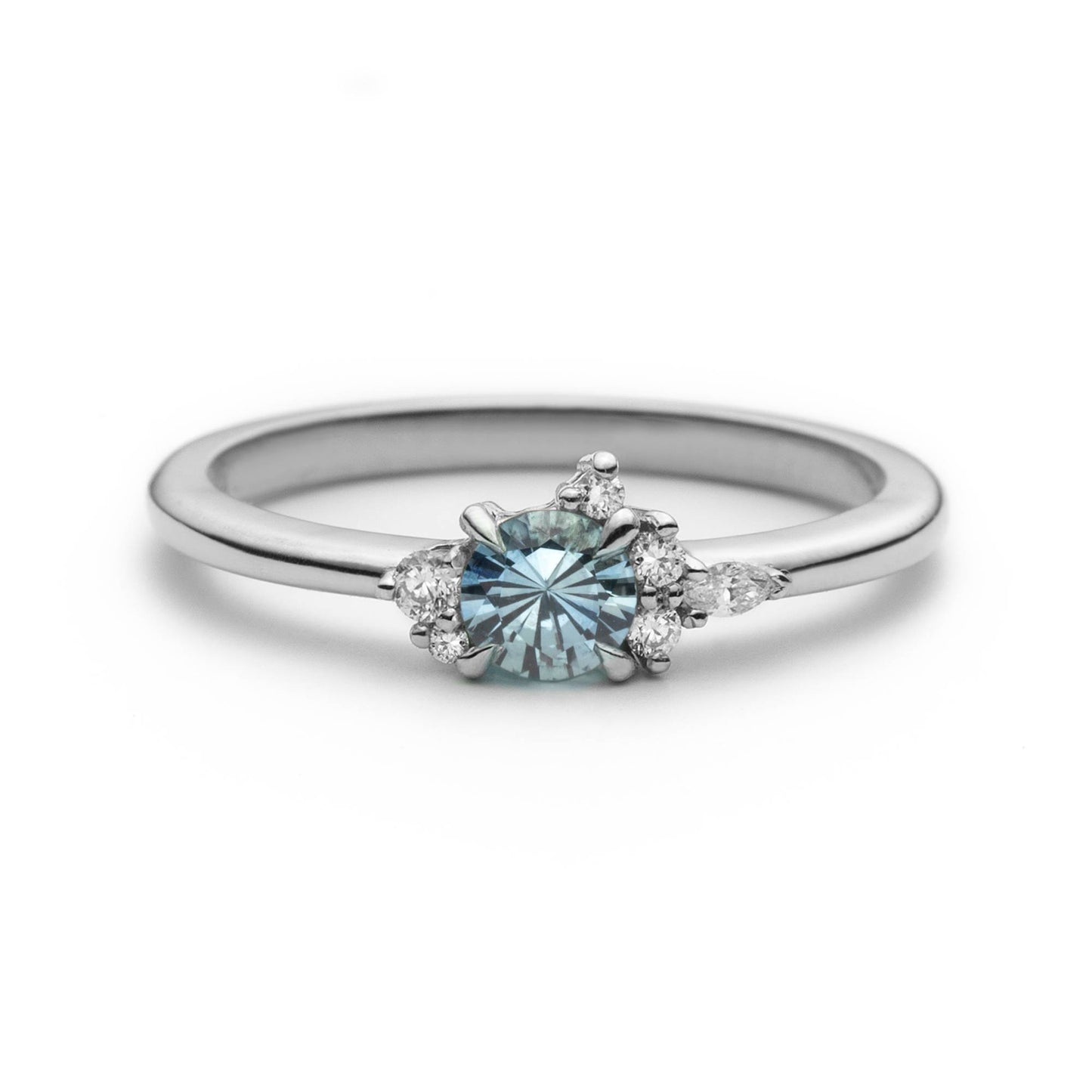 Bague de fiançailles en saphir bleu rond de 0,35ct et diamants naturels en or blanc 14k, vue de face sur fond blanc montrant la couleur de la pierre et le cluster asymétrique