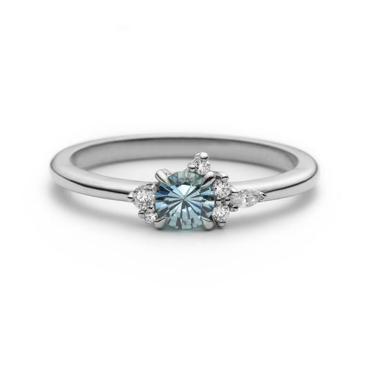 Bague de fiançailles en saphir bleu rond de 0,35ct et diamants naturels en or blanc 14k, vue de face sur fond blanc montrant la couleur de la pierre et le cluster asymétrique