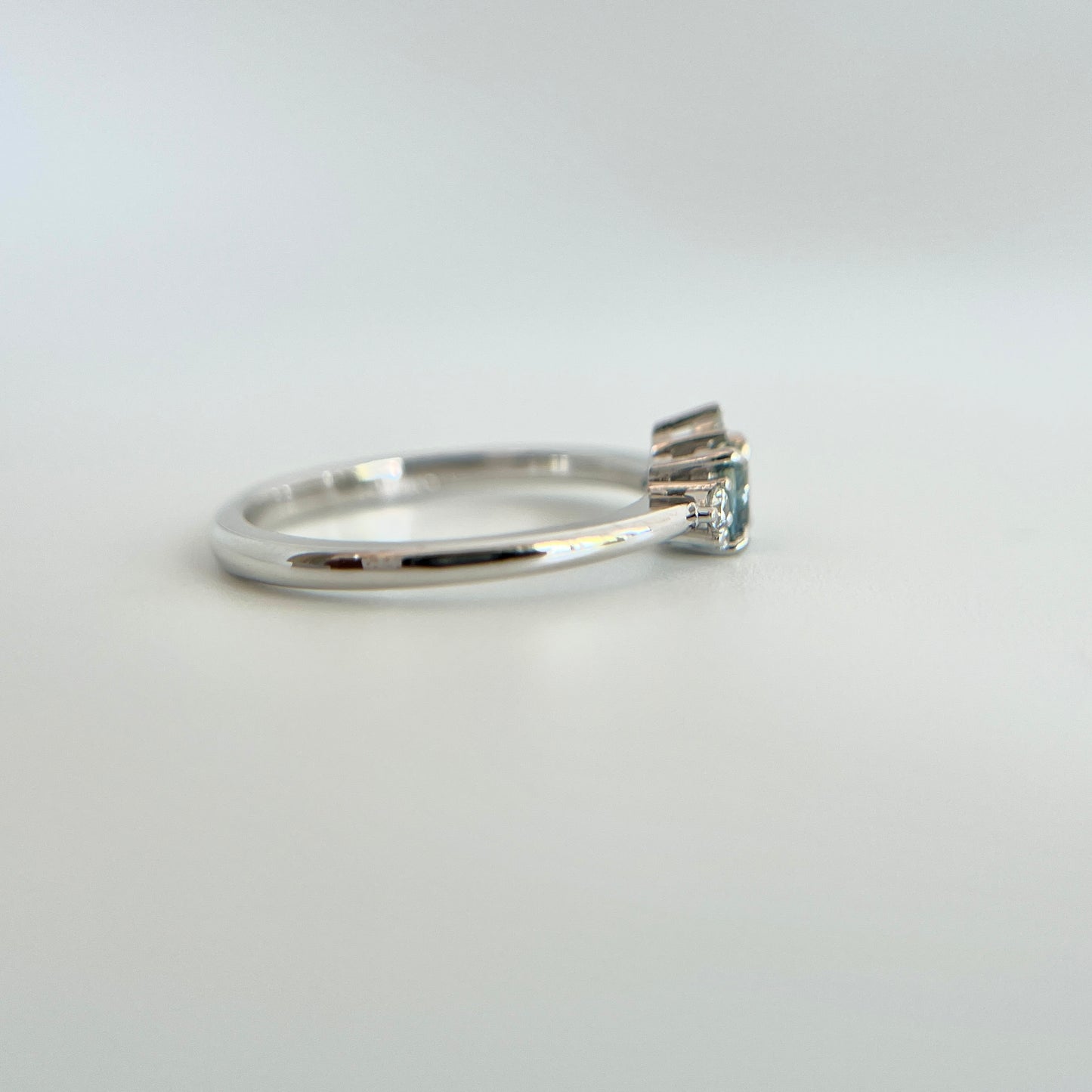 Bague de fiançailles en saphir bleu rond de 0,35ct et diamants naturels en or blanc 14k, vue de côté montrant le profil du corps de bague et la hauteur du serti