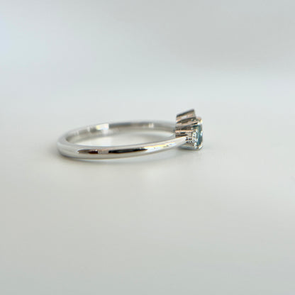 Bague de fiançailles en saphir bleu rond de 0,35ct et diamants naturels en or blanc 14k, vue de côté montrant le profil du corps de bague et la hauteur du serti