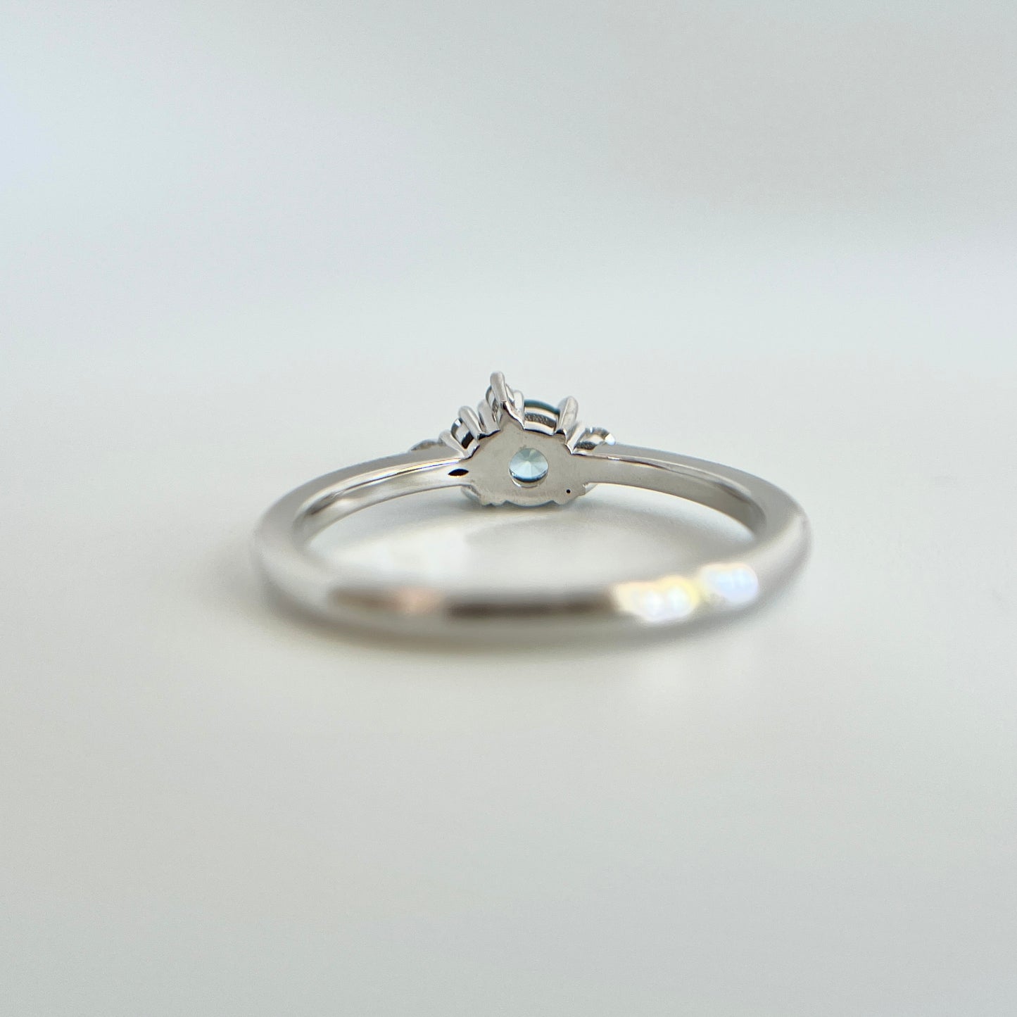 Bague de fiançailles en saphir bleu rond de 0,35ct et diamants naturels en or blanc 14k, vue du dessous montrant la construction du serti et le détail du corps de bague