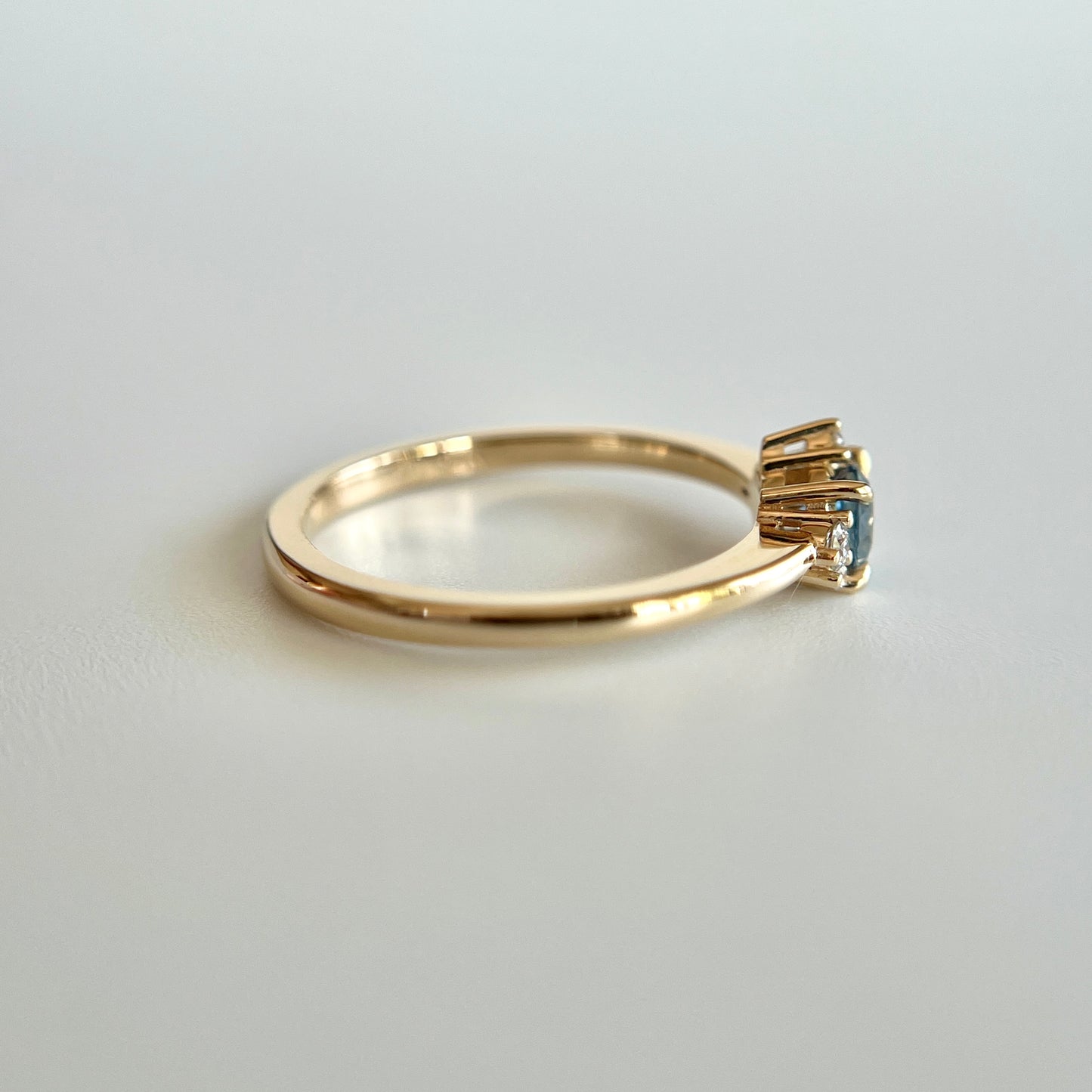 Bague de fiançailles en saphir bleu-sarcelle rond de 0,39ct et diamants naturels en or jaune 14k, vue de côté montrant le profil du corps de bague et la hauteur du serti