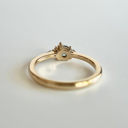 Bague de fiançailles en saphir bleu-sarcelle rond de 0,39ct et diamants naturels en or jaune 14k, vue du dessous montrant la construction du serti et le détail du corps de bague