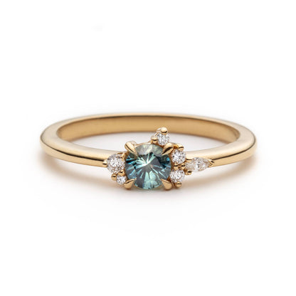 Bague de fiançailles en saphir sarcelle rond de 0,38ct et diamants naturels en or jaune 14k, vue de face sur fond blanc montrant la couleur de la pierre et le cluster asymétrique