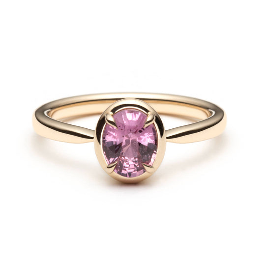 Bague de fiançailles solitaire en saphir ovale rose-orangé de 1,20ct en or jaune 14k avec serti en griffes à cadre en or, vue de face sur fond blanc montrant la couleur complète de la pierre