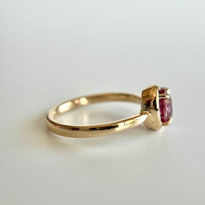 Bague de fiançailles solitaire en saphir ovale rose-orangé de 1,20ct en or jaune 14k, vue de côté montrant le profil du corps de bague et la hauteur du serti
