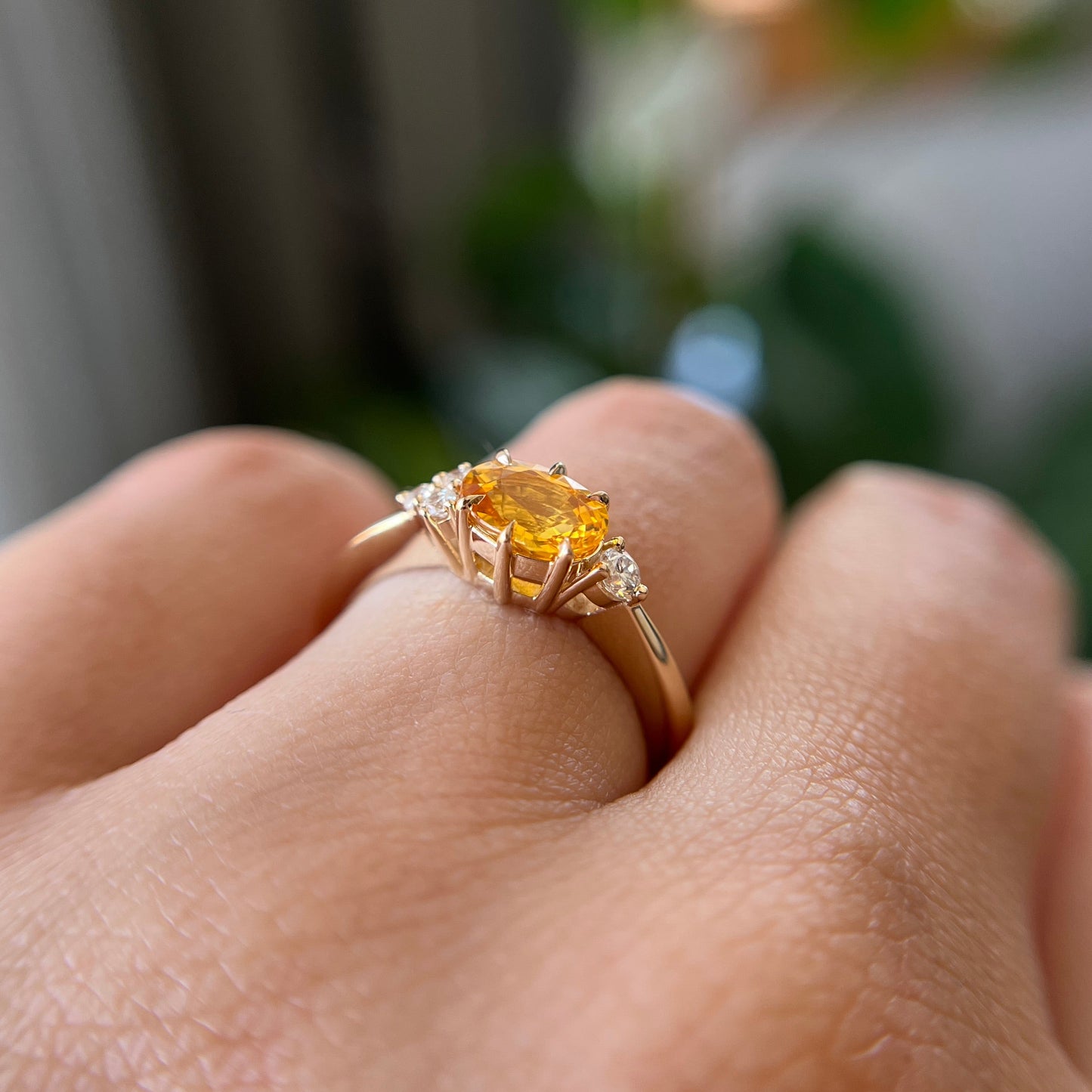 Bague en saphir jaune vif ovale et diamants en or jaune 14k, vue de côté portée au doigt montrant les accents de diamants asymétriques et la hauteur du serti