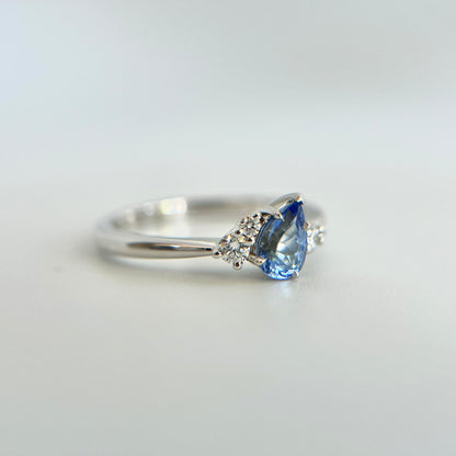 Bague de fiançailles en saphir bleu taille poire de 0,52ct du Sri Lanka et diamants naturels en or blanc 14k, vue en angle montrant la pierre inclinée et le détail du serti de diamants