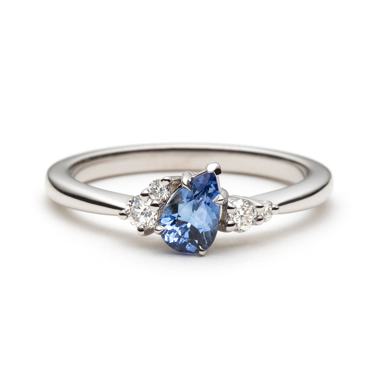 0.52ct pear shape blue Sri Lanka sapphire and natural diamond cluster engagement ring in 14k white gold, front view on white background showing tilted gemstone and asymmetric diamond setting