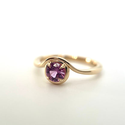 Pink sapphire solitaire ring in 14k yellow gold, side view showing wave band and setting detail