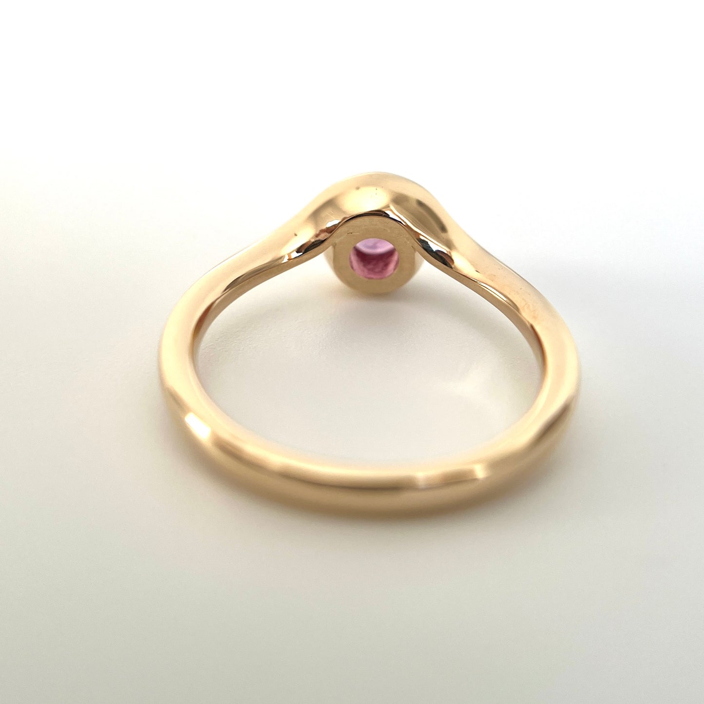 Pink sapphire solitaire ring in 14k yellow gold, underside view showing setting construction and band detail