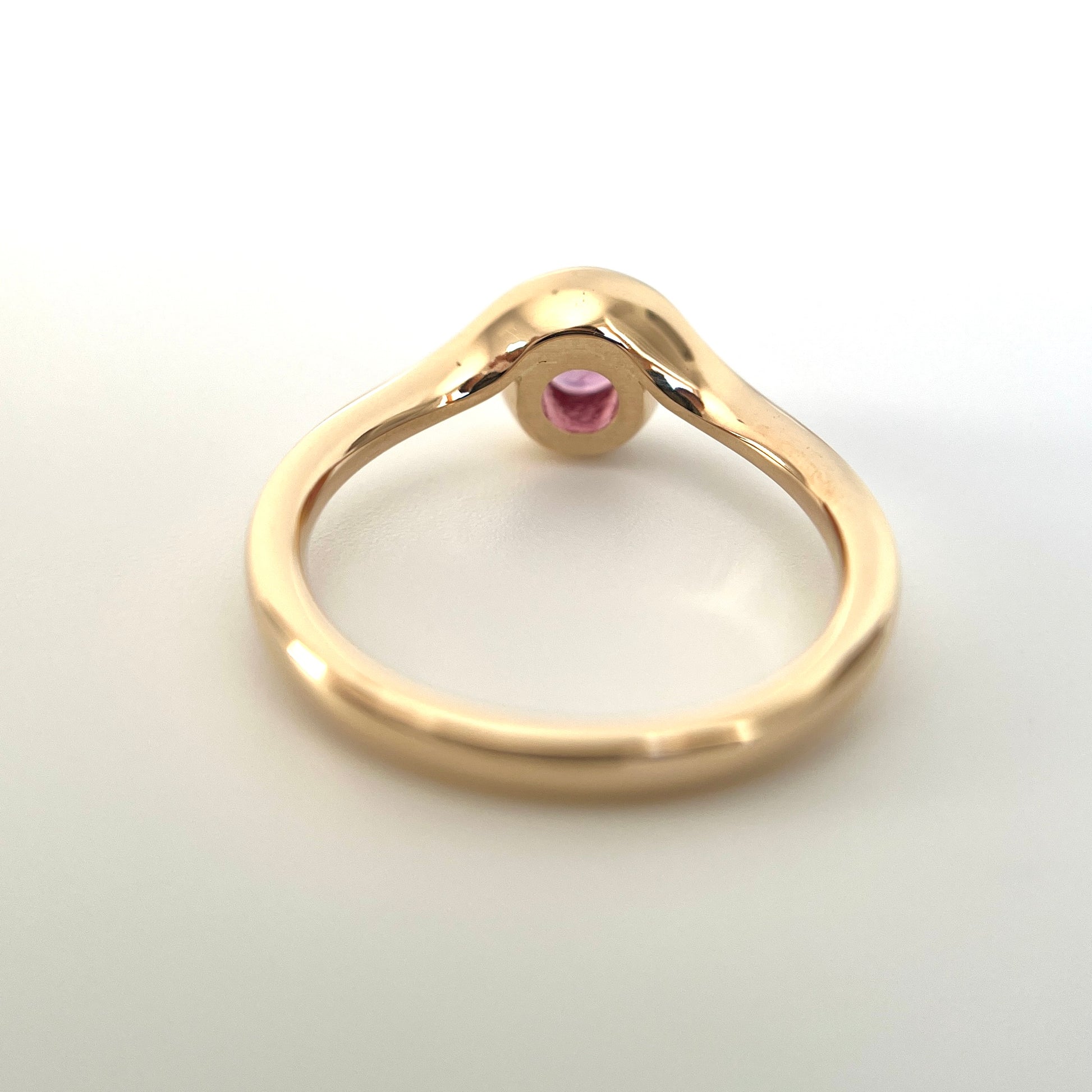 Pink sapphire solitaire ring in 14k yellow gold, underside view showing setting construction and band detail