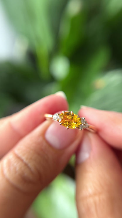1.05ct oval bright yellow Sri Lankan sapphire and diamond ring in 14k yellow gold, held in hands showing stone colour and asymmetric diamond accents in motion