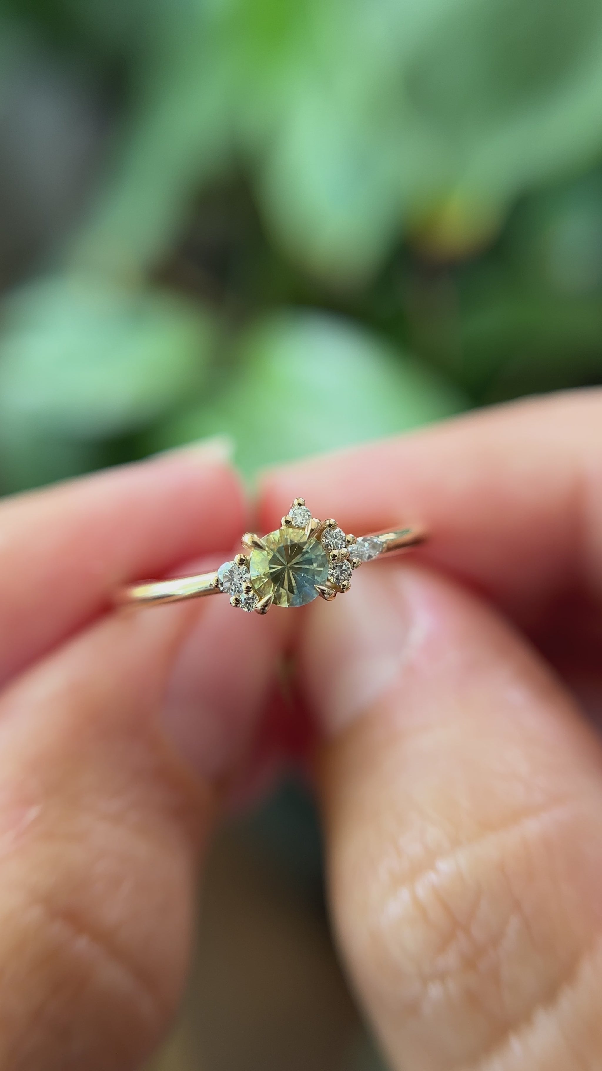 0.36ct round bi-color yellow to blue sapphire and natural diamond constellation engagement ring in 14k yellow gold, held in hands showing gemstone colour shift and faceting