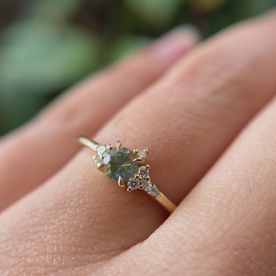 0.36ct round bi-color yellow to blue sapphire and natural diamond constellation engagement ring in 14k yellow gold, worn on finger showing gemstone colour shift and diamond cluster detail