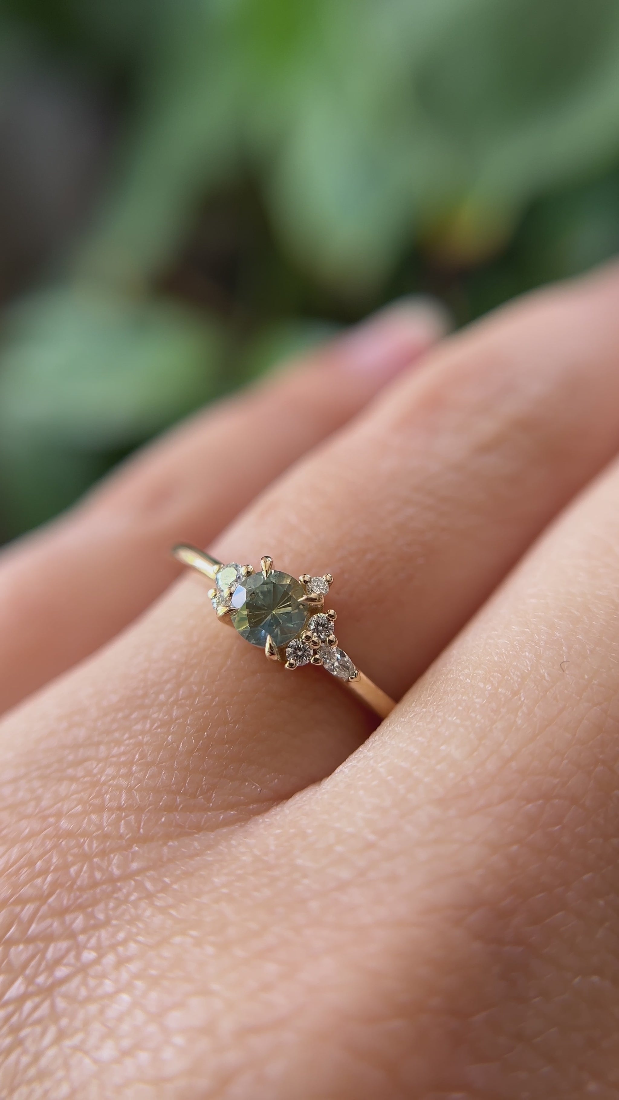 0.36ct round bi-color yellow to blue sapphire and natural diamond constellation engagement ring in 14k yellow gold, worn on finger showing gemstone colour shift and diamond cluster detail