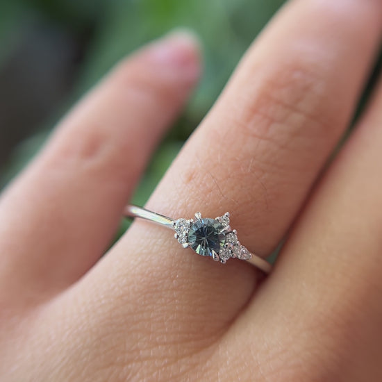 0.35ct round blue sapphire and natural diamond constellation engagement ring in 14k white gold, worn on finger showing gemstone colour and diamond cluster detail