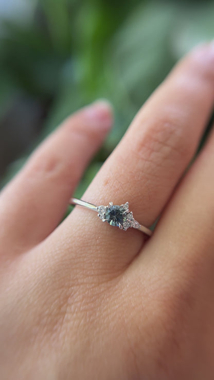 0.35ct round blue sapphire and natural diamond constellation engagement ring in 14k white gold, worn on finger showing gemstone colour and diamond cluster detail