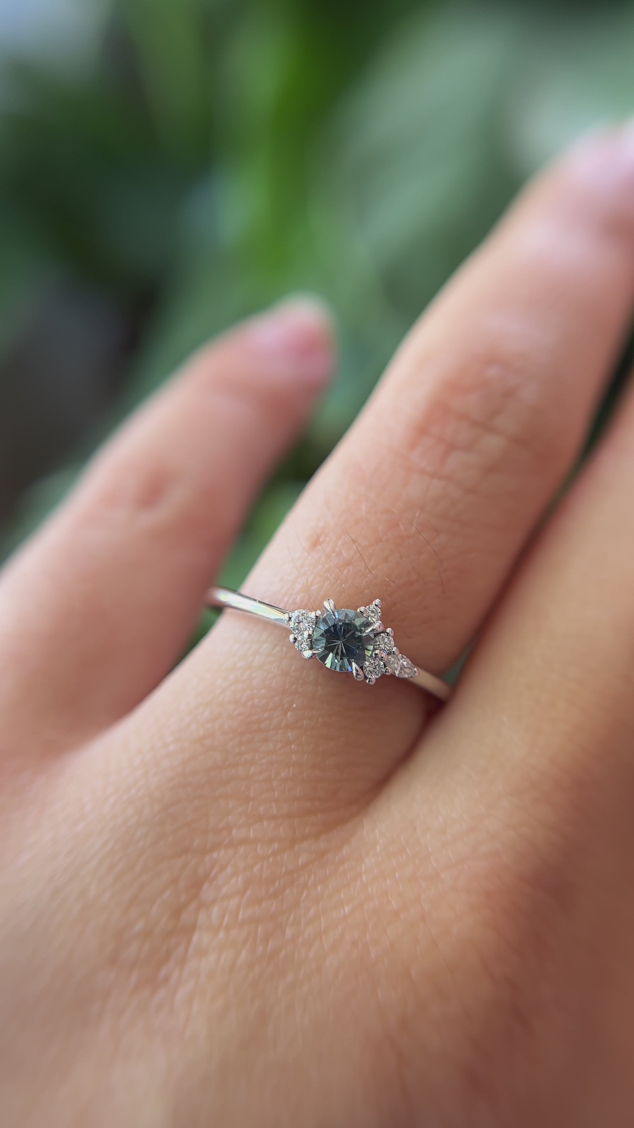 0.35ct round blue sapphire and natural diamond constellation engagement ring in 14k white gold, worn on finger showing gemstone colour and diamond cluster detail