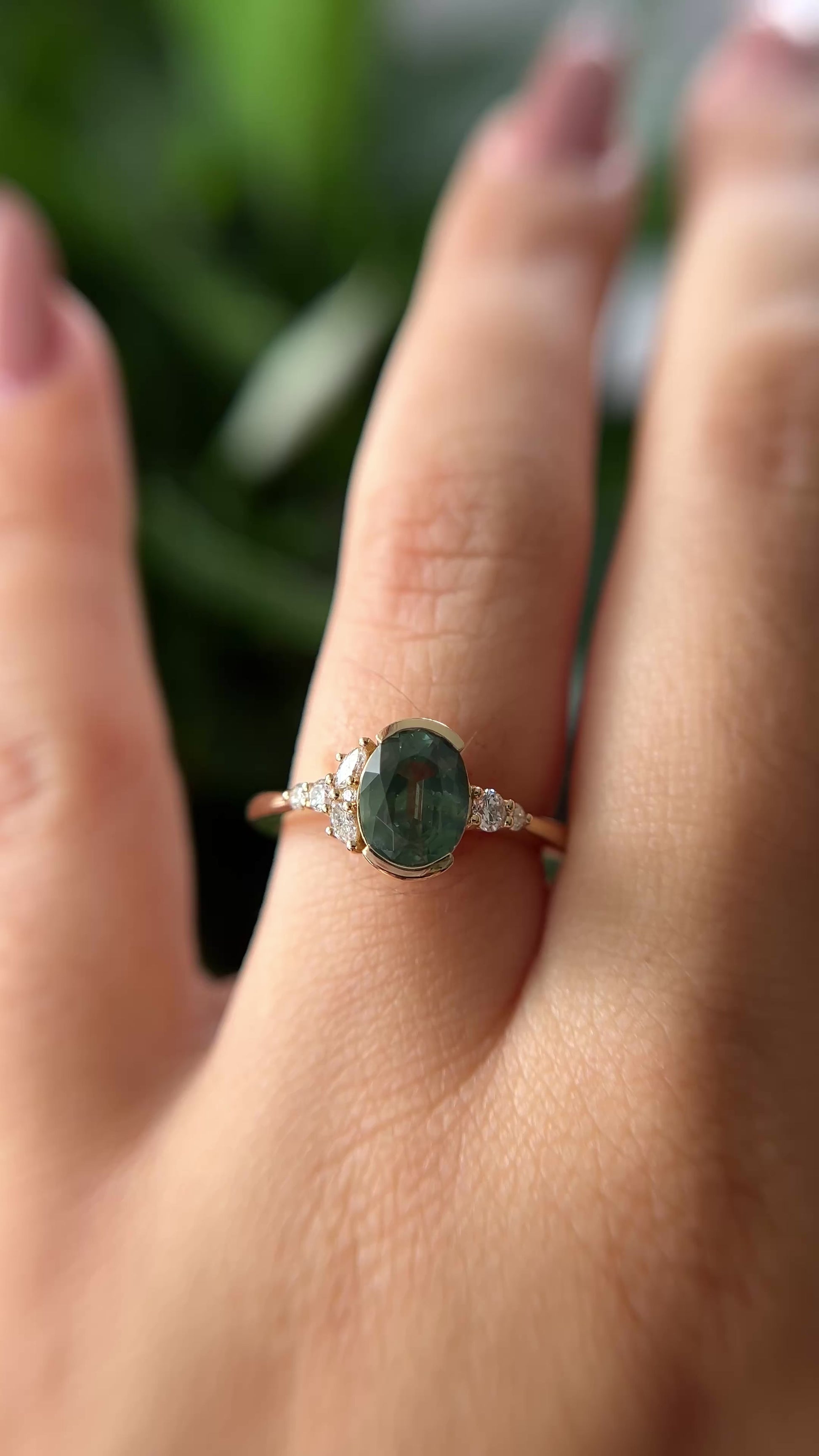 Oval green sapphire and natural diamond asymmetrical ring. The video shows the array of color from the center stone, and the sparkling side diamonds.  