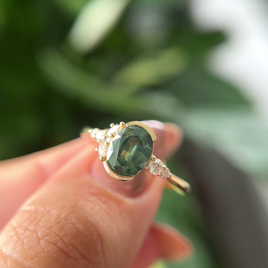 14k yellow gold, and oval green sapphire ring with accent diamonds, held in hand to show different angles. 