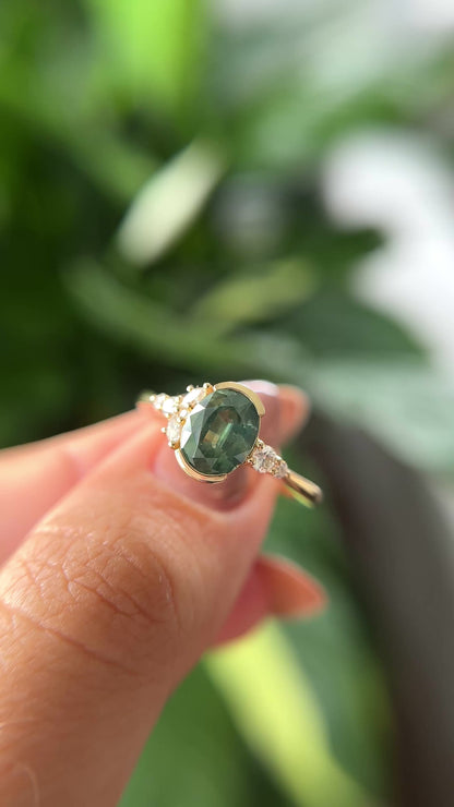14k yellow gold, and oval green sapphire ring with accent diamonds, held in hand to show different angles. 