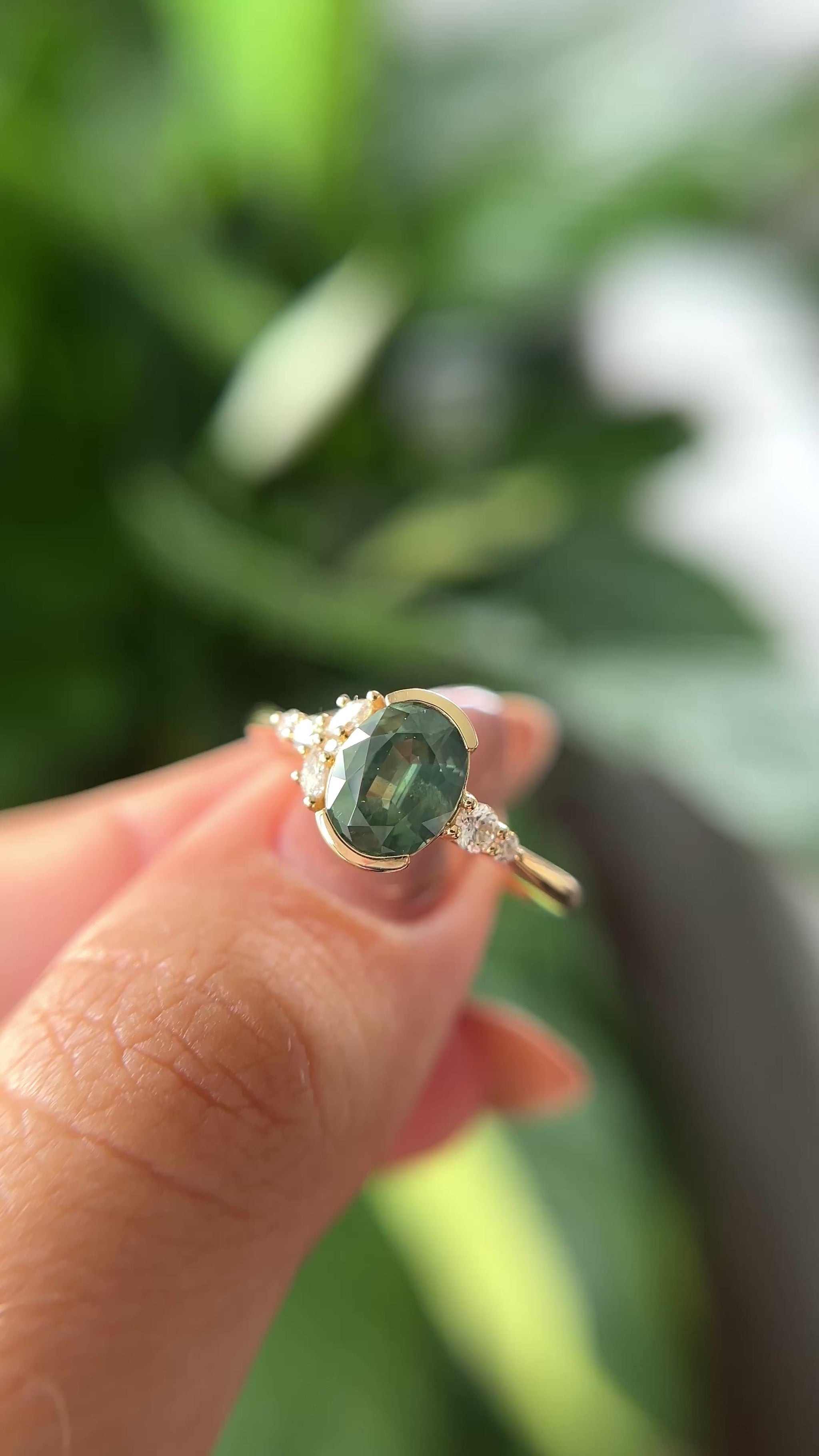 14k yellow gold, and oval green sapphire ring with accent diamonds, held in hand to show different angles. 