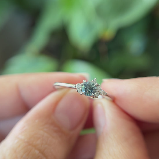 0.35ct round blue sapphire and natural diamond constellation engagement ring in 14k white gold, held in hands showing gemstone colour and faceting